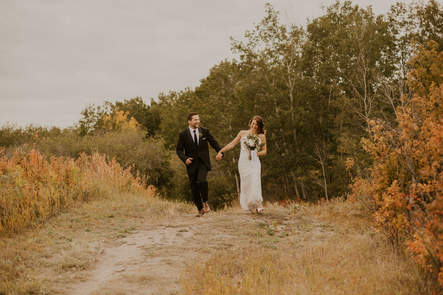 bride and groom running across field in Regina, Saskatchewan