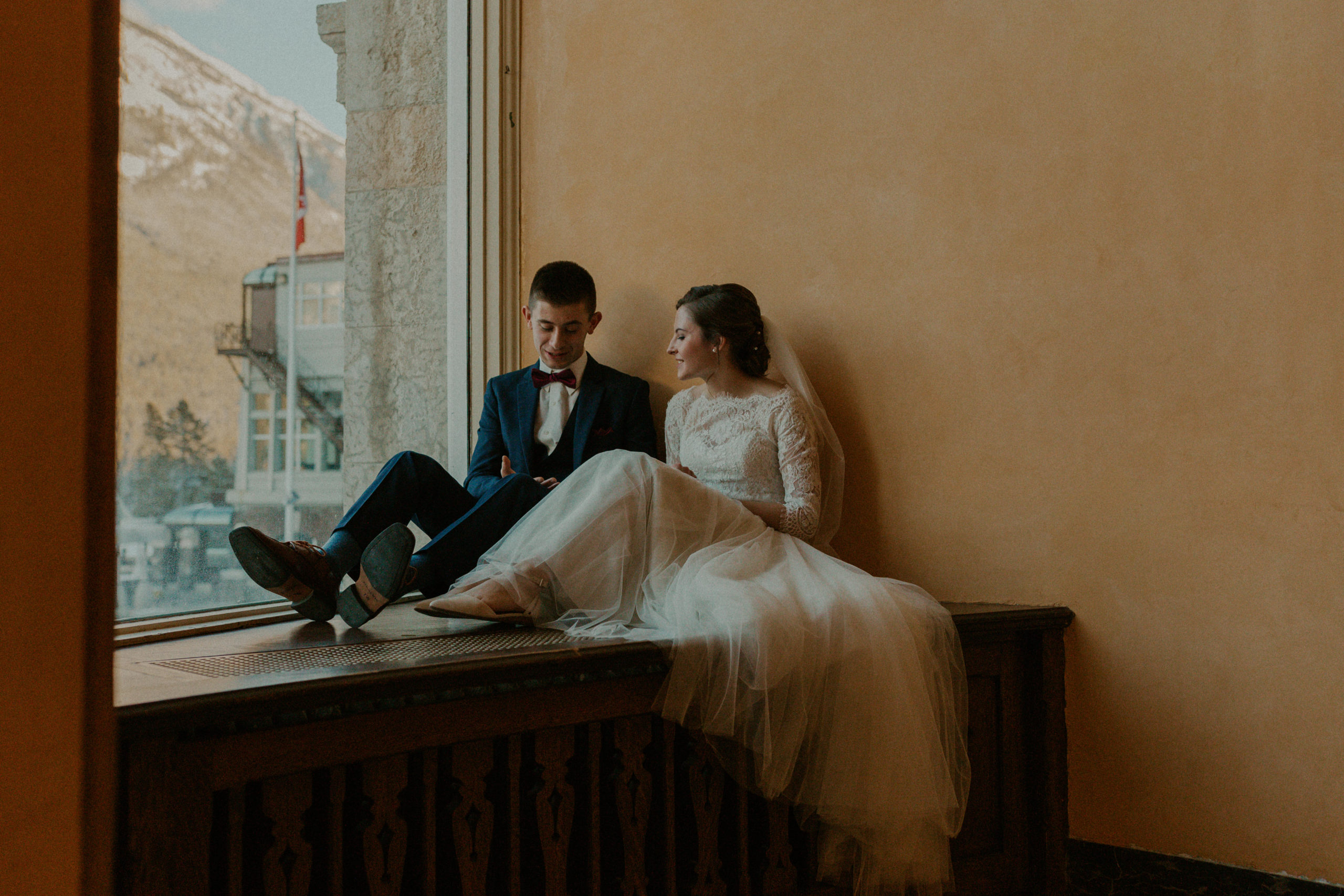 Couple sitting by window on wedding day
